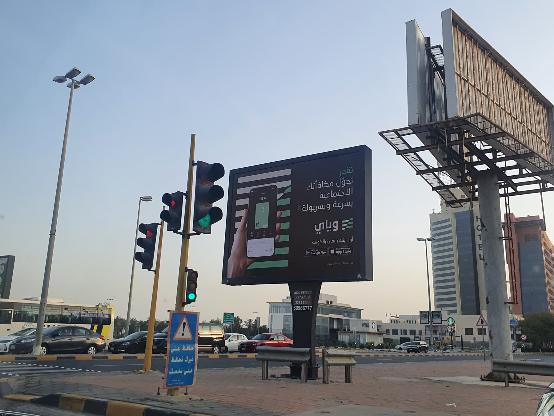 A digital billboard at a road junction in Kuwait showing a hand holding a phone with the Weyay app, next to Arabic text and the Weyay logo.